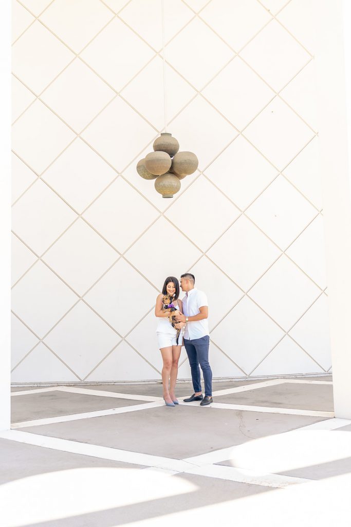 A wedding couple posing in front of a white building captured by a photographer in Los Angeles.