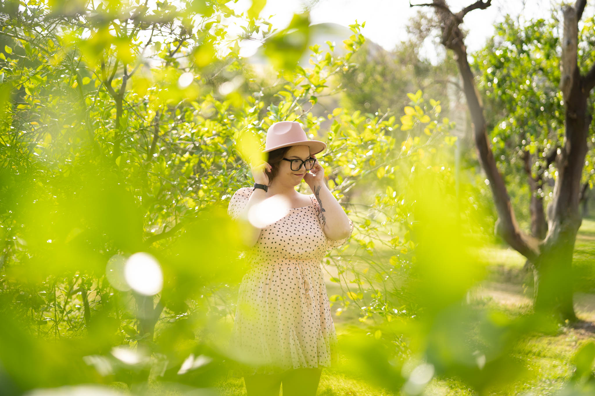 ThomasKim_photography A woman in a hat is talking on the phone during her K & S Engagement Session in an orchard.