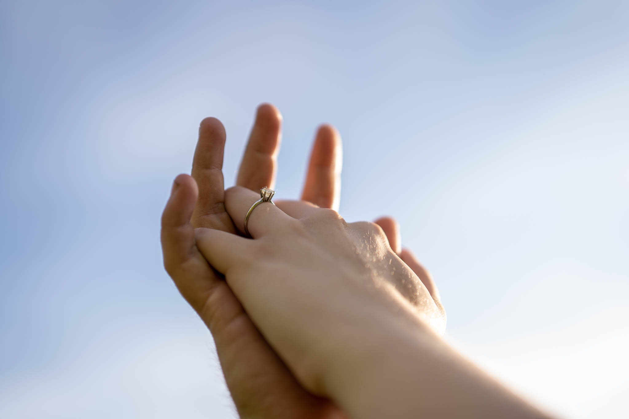 ThomasKim_photography K & S Engagement Session featuring hands reaching up against a blue sky.