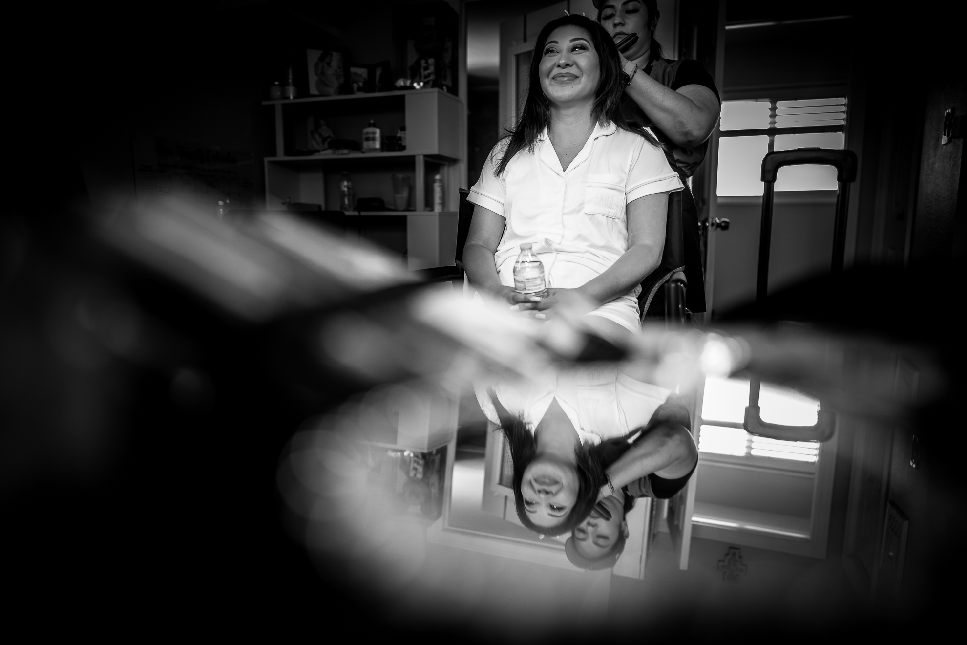 ThomasKim_photography A woman is getting her hair done in front of a mirror at a salon.