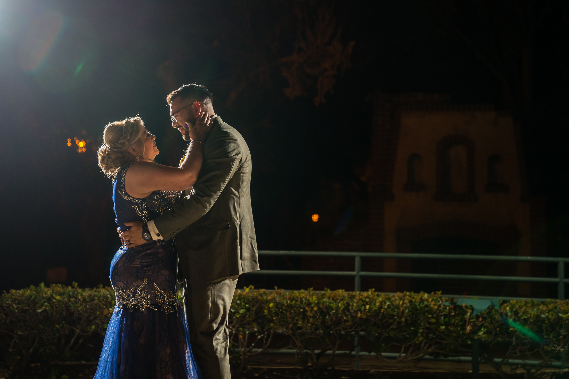ThomasKim_photography A bride and groom embrace in front of a light at night during their special moment (S&A).