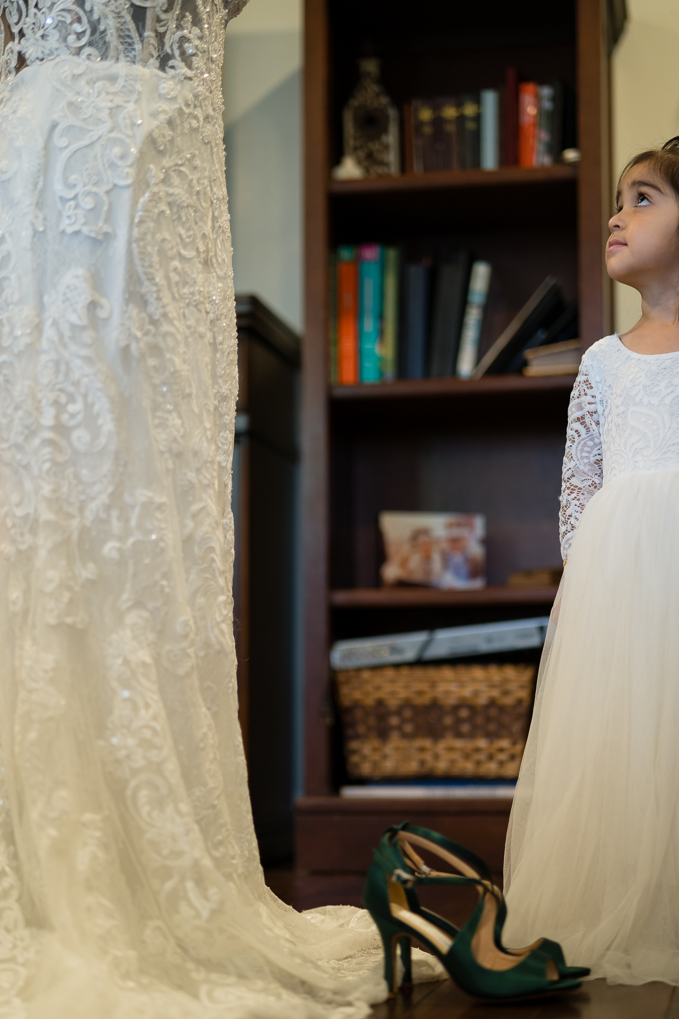 ThomasKim_photography A little girl in a white wedding dress shyly looking at her shoes.
