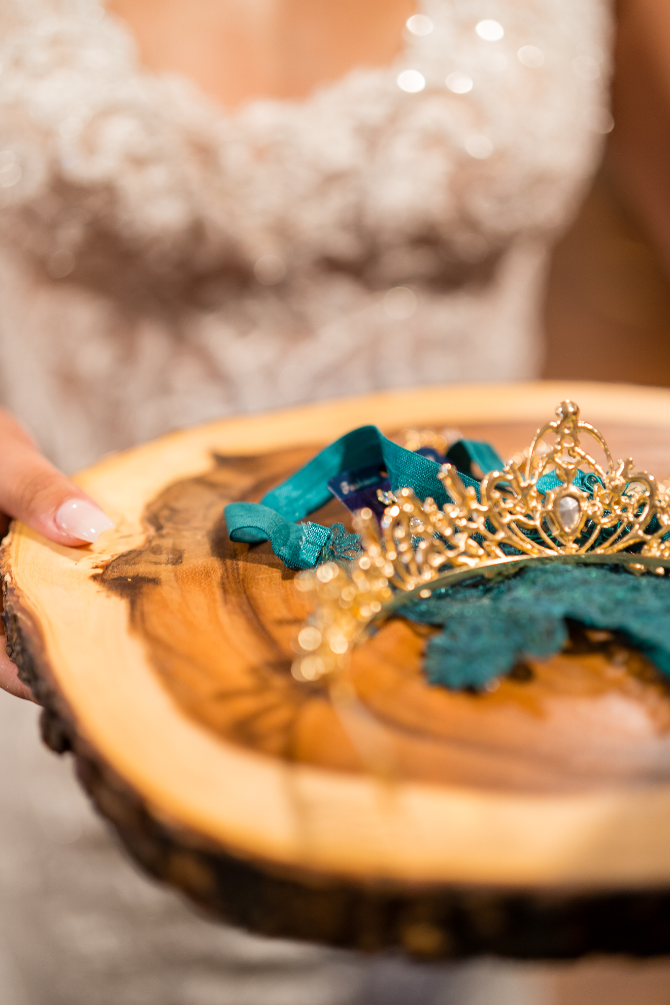 ThomasKim_photography A bride holding a tiara on a wooden plate for her wedding celebration.