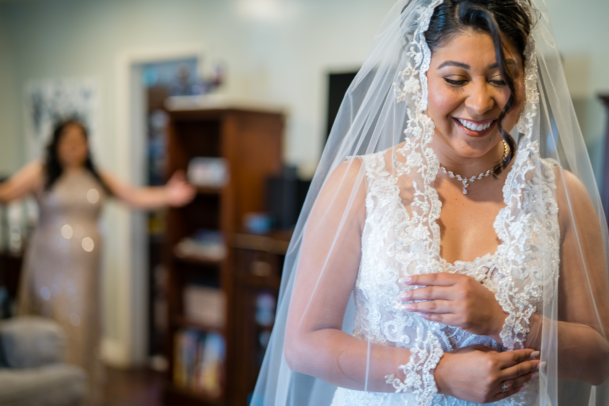 ThomasKim_photography A bride smiles as she puts on her wedding veil, showcasing joy and anticipation.
