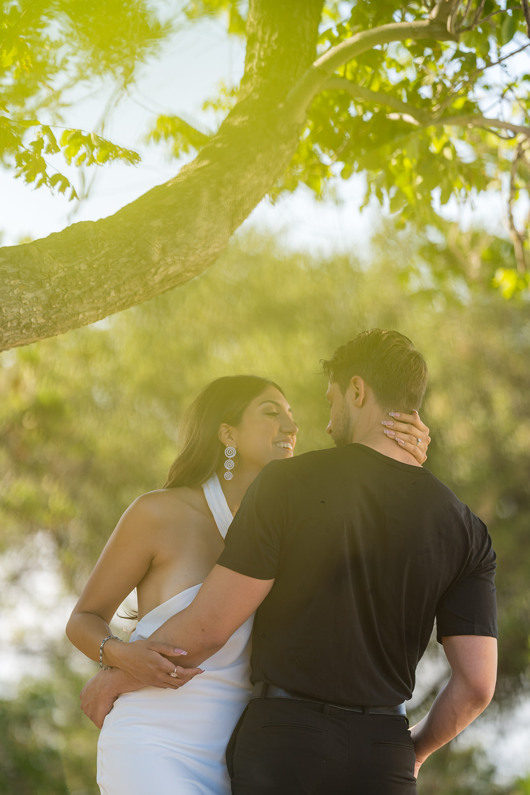 ThomasKim_photography A man and woman embrace during their V & J engagement session under a tree.